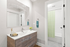 Modern bathroom featuring sleek sink with wooden vanity, large mirror, and bright shower area with green checkered curtain.