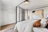 Modern bedroom with elegant bedding, mirrored closet doors, and stylish artwork, offering a serene and sophisticated retreat.