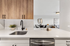Modern kitchen with sleek cabinetry, elegant countertop, and integrated sink, featuring a view into a stylish living area.