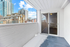 Bright balcony view with modern buildings and snow-covered floor, featuring sleek sliding glass doors and a white brick wall.
