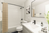 Modern bathroom with tasteful decor, featuring a sleek vanity, minimalist fixtures, and elegant tiled bathtub.