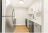 Modern kitchen featuring stainless steel appliances, sleek white cabinetry, and elegant wood flooring.