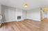 Bright and spacious living room with elegant wood flooring and a chic white brick fireplace, perfect for cozy evenings.