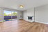 Bright living room with sleek wooden floors, a modern white brick fireplace, and expansive sliding glass doors leading to a scenic balcony.