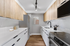 Modern kitchen featuring sleek white countertops, wood cabinetry, stainless steel appliances, and elegant track lighting.