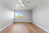 Bright, spacious bedroom with modern ceiling fan, large window offering natural light, and elegant wood flooring.