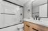 Modern bathroom design featuring sleek black faucets, elegant glass shower doors, and a stylish wood vanity.
