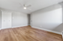 Bright and spacious room with elegant wood flooring, sleek white closet doors, and a modern ceiling fan.