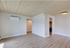 Modern living area with elegant wood flooring, stylish ceiling finish, and a glimpse into a sleek kitchen.