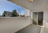 Charming balcony with white brick walls, offering a serene outdoor space with views of nearby buildings and trees.