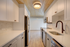 Modern kitchen with sleek white cabinetry, stainless steel appliances, and warm wooden ceiling panels.