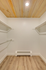 Bright and spacious walk-in closet with natural wood flooring and ceiling shelves, perfect for ample storage.