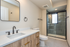 Contemporary bathroom featuring a sleek vanity with dual faucets, large mirror, and elegant glass shower enclosure.