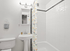 Bright and modern bathroom featuring sleek white tiles, elegant pedestal sink, and stylish lighting fixtures.