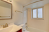 Bright, freshly renovated bathroom with a classic white tile design, sleek modern fixtures, and a sunlit window for a serene atmosphere.