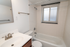Bright, modern bathroom with sleek fixtures, a bathtub, and frosted window for natural light and privacy.