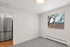 Bright room with large window, modern stainless steel refrigerator, and soft carpet flooring.