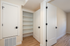 Bright hallway featuring sleek hardwood floors and a spacious open closet with modern shelving.