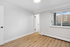 Bright room with sleek hardwood flooring, large window for natural light, and modern white door design.