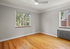 Bright bedroom with polished wooden floors, large windows offering natural light and a peaceful view of greenery.