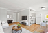 Bright and welcoming living area with modern decor, showcasing a cozy seating arrangement and seamless access to a sleek kitchen with contemporary appliances.