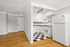Bright, compact kitchen with a classic black and white checkered floor, featuring modern appliances and ample cabinet space, opens to a cozy, hardwood living area.
