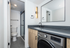 Modern bathroom featuring sleek black fixtures, a large mirror, and an in-unit washer and dryer.