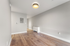 Bright and spacious room with sleek laminate flooring and modern lighting fixture, perfect for a cozy ambiance.