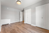 Bright, airy room with sleek wood flooring and modern white closets, offering a blank canvas for personalization.