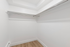 Spacious walk-in closet featuring sleek wooden flooring, ideal for organization and storage solutions.