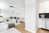 Bright and modern living space featuring a cozy sectional sofa, stylish decor, and sleek kitchen with stainless steel appliances.
