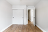 Bright and spacious bedroom with sleek wood flooring, modern white closet doors, and an inviting open doorway.