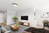 Modern and inviting living room with elegant decor, featuring a stylish coffee table, cozy sectional sofa, and mounted flat-screen TV, accented by a lush houseplant and geometric artwork.