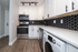 Modern kitchen with sleek black hexagonal backsplash, stainless steel appliances, and elegant white cabinetry.