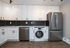 Modern kitchen with sleek stainless steel appliances, elegant white cabinets, and stylish black hexagonal backsplash.