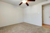 Cozy bedroom with plush carpeting and a ceiling fan, offering ample natural light and a serene atmosphere.