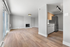 Inviting open-plan living space with chic wooden flooring, modern kitchen, and a cozy fireplace, perfect for comfortable and stylish living.