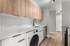 Modern kitchen with sleek wood cabinets, white countertops, and stainless steel appliances featuring a stylish black faucet.