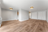Spacious modern living area with elegant wood flooring and stylish lighting, perfect for comfort and convenience.