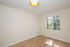 Bright room with natural light, showcasing polished hardwood floors and a large window with open views.