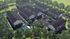 Aerial view of a modern apartment complex surrounded by lush greenery and parking facilities.