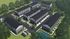 Aerial view of a modern apartment complex surrounded by lush greenery and landscaped gardens.