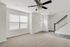Inviting entryway with plush carpet, large window, and modern ceiling fan, leading to a staircase.