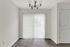 Elegant apartment nook with large sliding glass door and vertical blinds, featuring a classic chandelier.