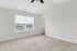 Inviting bedroom with soft carpet flooring and large window, filling the space with natural light.