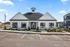 Charming modern building with gable roof, large windows, and inviting entrance surrounded by well-maintained landscaping.