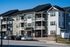 Modern apartment complex with stylish balconies and ample parking, featuring elegant siding and a pristine exterior under a clear blue sky.