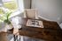 Elegant home office space with a rustic wooden desk, cozy beige chair, and bright window lighting. Features luxury decor with a ceramic vase of white flowers and an open magazine for inspiration.
