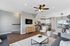 Modern open-concept living room with elegant ceiling fan, cozy seating area, and sleek kitchen featuring stainless steel appliances and large windows offering scenic views.