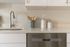 Modern kitchen detail showcasing sleek stainless steel appliances, elegant white cabinetry, and stylish countertop accessories.